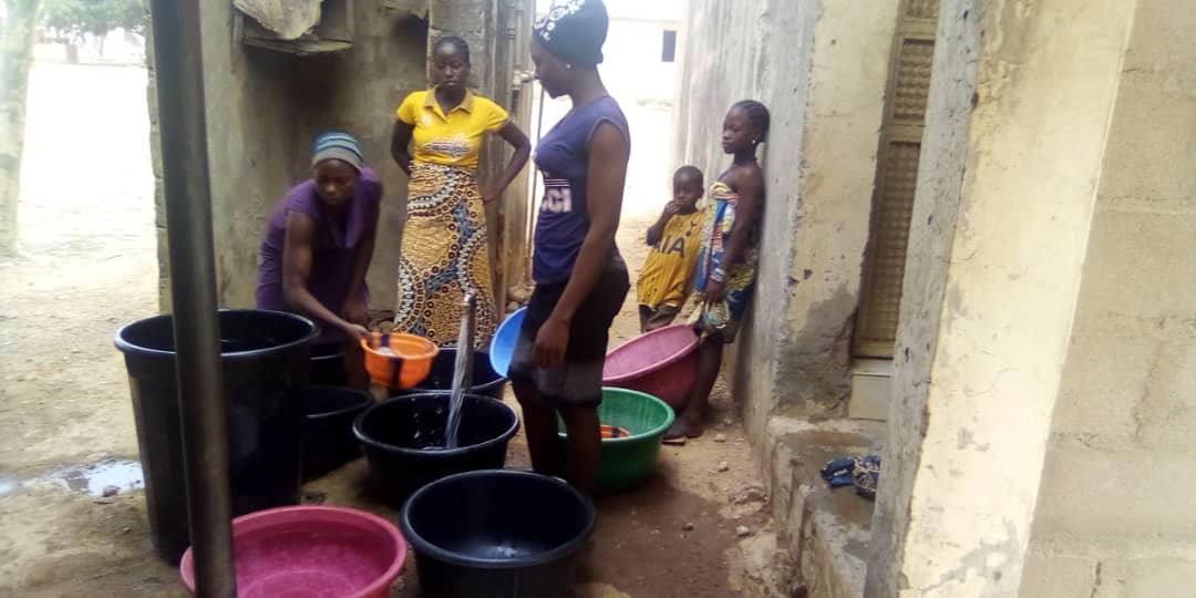 Nigerianische Frauen fangen Wasser auf